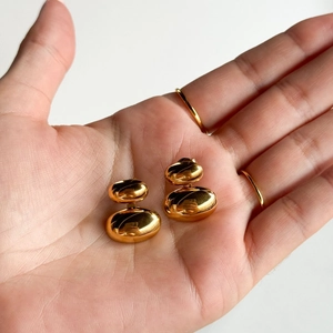 Macro view of polished 18k gold plated double ball earrings on a hand for size reference