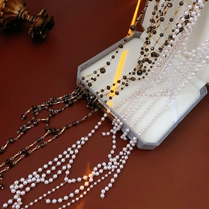 Detail of multi-layer glass pearl and black faceted bead tassel necklace on velvet box