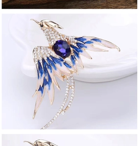 Macro detail of phoenix brooch with purple gemstone, blue enamel wings and rhinestone tassels