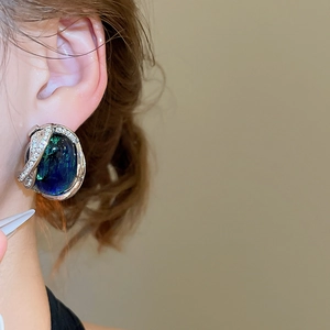 Gros plan sur les boucles d'oreilles vintage en résine avec pierre bleue et zircons