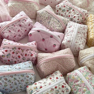 Detail of floral and strawberry pattern cosmetic bags with quilted texture and zippers