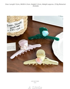 Detailed view of large acetate tulip hair claws in soft pastel green and cream tones