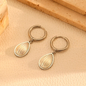 Detailed close-up of silver drop earrings with shell texture inlays on leather surface