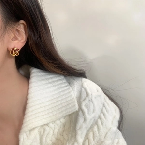 Close-up of vintage knot earrings in gold and burgundy red on a female model