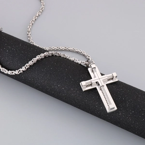 Detailed close-up of stainless steel cross pendant with twisted wire rope texture