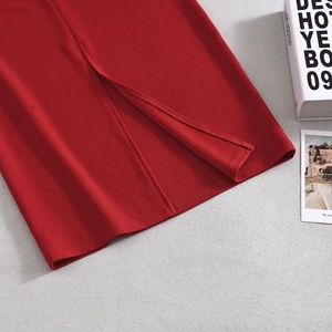 Detail of red knitted dress slit hemline with fashion magazines on textured background