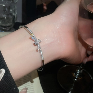 Détail d'un bracelet nœud argenté orné de zircons scintillants au poignet d'un mannequin