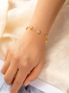 Detail of star-shaped charms with clear zircons on a gold-tone stainless steel bracelet