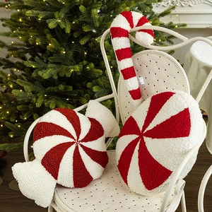 Christmas candy pillows and candy cane cushions on a chair with a tree backdrop