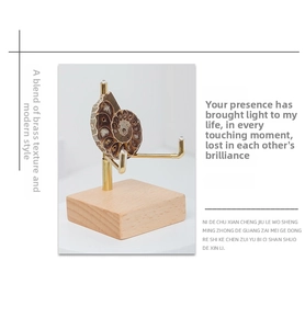 Detail of walnut wood and brass stand supporting an ammonite fossil on white background