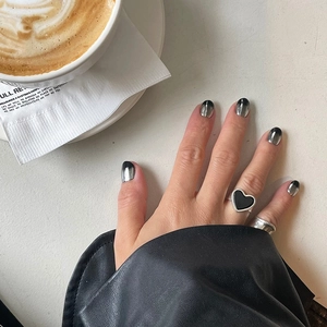 Close-up of heart-shaped black onyx ring and silver band on a hand at a cafe table