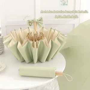 Gros plan du parapluie pliant vert menthe avec nœud décoratif et sa housse de rangement
