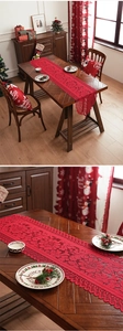 Close-up of red Christmas lace table runner with intricate hollow patterns and fringe edge