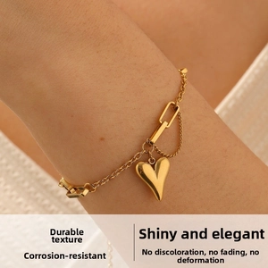 Detail shot of a gold-plated heart pendant bracelet with thick geometric chain on wrist