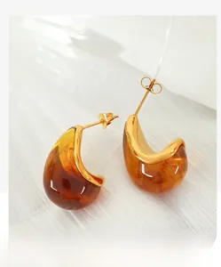 Detailed shot of amber resin earrings with gold edges on white textured fabric