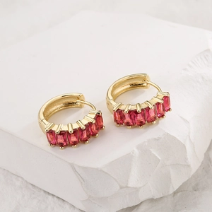 18K gold-plated hoop earrings with five baguette-cut red zircons on stone background