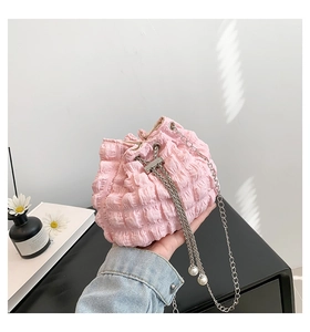 Detail of pink pleated drawstring handbag with silver chain and elegant pearl accents