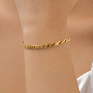 Detail shot of a minimalist gold woven mesh bracelet worn on a female wrist
