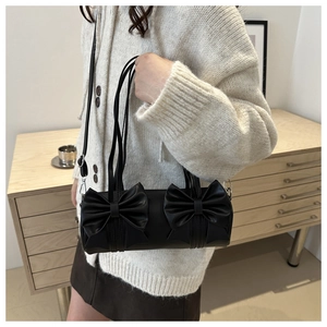 Détail d'un sac cylindrique en cuir noir orné de deux grands nœuds décoratifs en 3D