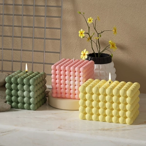 Tre candele a bolla accese in rosa, giallo e verde pastello per decorazioni di interni