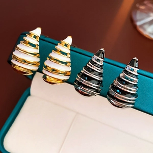 Detailed view of vintage spiral drop earrings in gold-white and silver-black enamel