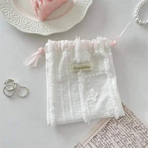 Detailed embroidery and lace mesh texture on a white drawstring storage pouch