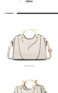 Detail of white handbag featuring cat-ear gold metal handles and adjustable shoulder strap