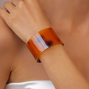 Close-up of a wide open-cuff bracelet with amber tortoiseshell pattern on wrist