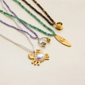 Detail of multi-layer beaded necklaces with crab, headphone, and surfboard pendants