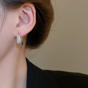 Detailed view of U-shaped silver earrings with micro-pave zircons on model ear