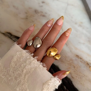 Polished 18k gold and silver irregular pebble rings displayed on marble surface