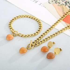 Detailed set of gold OT buckle jewelry with orange teardrop stone pendants on white texture