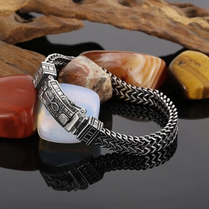 Détail d'un bracelet tissé en acier titane avec symbole de croix Ankh et texture gaufrée