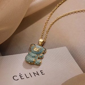 Gold-plated bear pendant necklace with turquoise zircon inlay on beige silk background