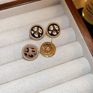 Detail of round leopard pattern earrings with white pearls in a beige velvet jewelry box