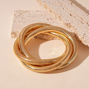 Detail of interlocking gold snake chain bracelet on natural travertine stone background