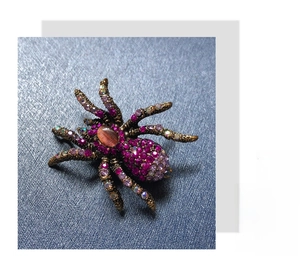 Detailed macro view of the vintage spider brooch with fuchsia rhinestones and cat eye stone