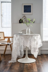 White lace floral tablecloth on a round table in a cozy home interior setting
