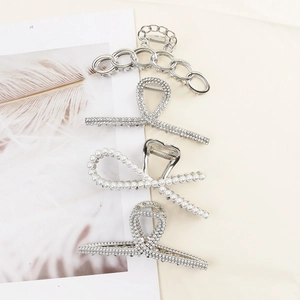 Set of 4 elegant silver metal hair claws with pearls and rhinestones on beige fabric