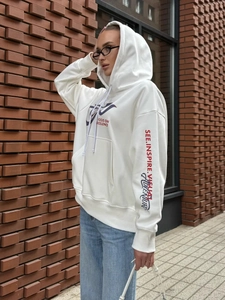 Streetwear white oversized hoodie with graphic prints on street style red brick background