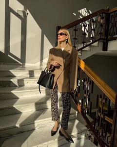 Détail d'un blazer marron avec un pantalon léopard sur un escalier en marbre
