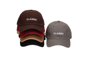Detailed embroidery of 'CLASSIC' text on multiple cotton twill baseball caps in various colors