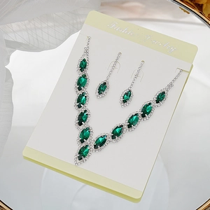 Detail of silver bridal necklace and earrings set with emerald marquise crystals