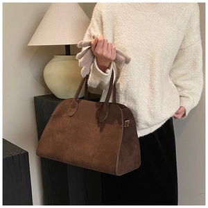 Dettaglio di una borsa tote a cartella in pelle scamosciata marrone scuro con texture opaca liscia