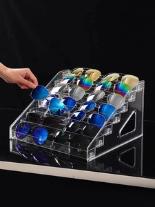 Macro shot of 6-tier transparent acrylic sunglasses display stand with a hand for scale