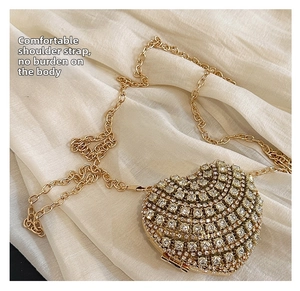 Détail d'un sac de soirée en forme de cœur doré avec strass brillants et bandoulière