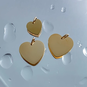Set of three polished golden heart-shaped stainless steel pendants with water droplets