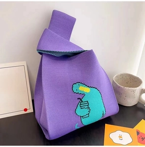 Detail of purple knitted tote bag with pixel art dinosaur and soft fabric texture