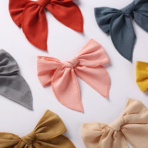 Flat lay of seven colorful linen cotton bow hair clips for girls in various pastel shades