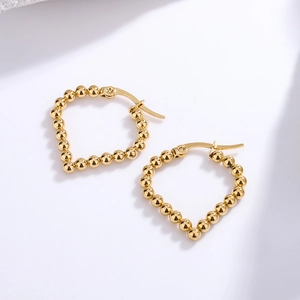 Close-up of golden beaded heart earrings in high-quality stainless steel metal